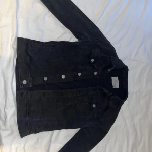 Svart jeansjacka från Zara - Säljer en snygg svart jeansjacka i bra skick. Den har en klassisk design med knappar framtill och två bröstfickor. Perfekt för höst och vår, och funkar till nästan alla outfits. Passar både till vardags och fest. Hör av dig om du är intresserad!