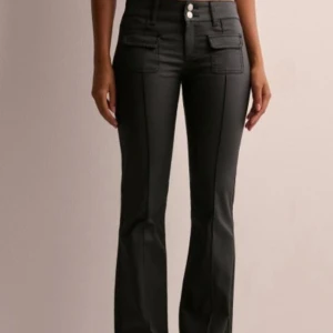 Svarta lågmidjade bootcut jeans från Nelly - Säljer ett par snygga svarta lågmidjade bootcut jeans från Nelly. De har coola fickdetaljer och en stilren design. Köpte dem för 699kr och var för små för mig så har aldrig använt dem!😊