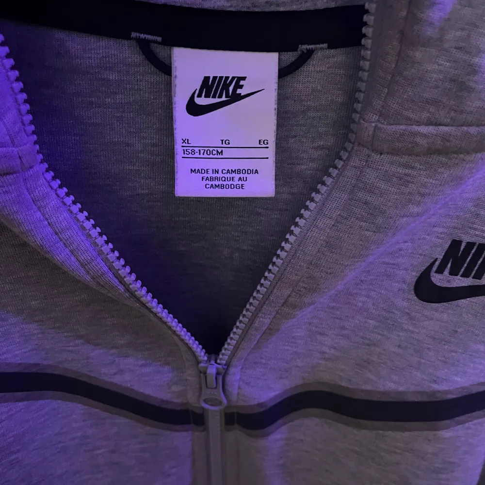 Säljer en grå hoodie från Nike i storlek XL. I barn Den har en dragkedja framtill och en klassisk Nike-logga på bröstet. Perfekt för både träning och vardag. Hoodien är i mycket bra skick och superbekväm att ha på sig. Passar perfekt till höst och vår!. Tröjor & Koftor.