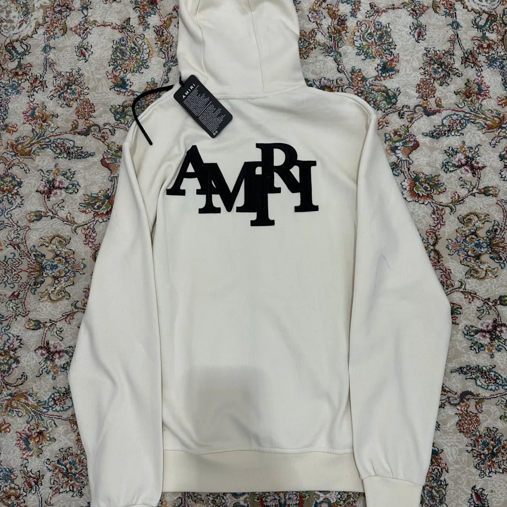 Säljer en snygg vit hoodie S-M Amiri. Observera att det finns en liten blå fläck på framsidan som går att ta bort. Suttit i garderoben o aldrig använt.. Hoodies.