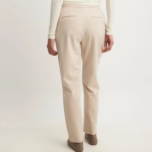 Beige kostymbyxor - Snygga beige kostymbyxor i normal passform. Perfekta för både kontoret och mer formella tillfällen. De har en klassisk design med raka ben och är tillverkade i ett bekvämt material som ger en stilren look. (Helt nya med prislapp) 