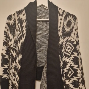 Svartvit mönstrad kofta - Säljer en superfin svartvit kofta med ett coolt geometriskt mönster. Koftan har en mysig ribbad krage. Perfekt för att hålla sig varm och stilren samtidigt! Inköpt på New Look i London. Garderobsrensning så kika gärna in övriga auktioner.