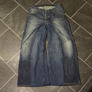 Blåa baggy flared jeans - Handgjorda baggy flared jeans med små distress detaljer och en sjukt nice wash. Storlek 33/32 eller 44cm i midjan, 107cm långa och 37,5cm i benöppningen. 