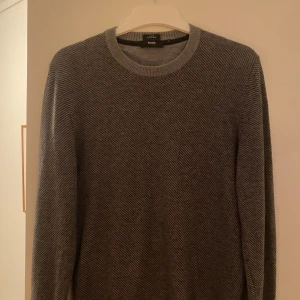 Stickad hugo boss tröja - Säljer en stilren grå tröja från Hugo boss tröja. Den är i ett sjukt skönt stickat materil och säljer den då den inte passar mig längre. Den är i stl S men passar om man har S-M i vanliga fall. Hör av er om ni vill ha bild med den på elr fler bilder. Den har inga tecken på användning!