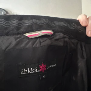 Svarta täckbyxor  från Áhkká - Säljer en svart outdoorjacka från Áhkká i storlek 40. Jackan har dragkedjor och är perfekt för kyligare väder. Den är tillverkad med áphiTec5.5 och MóurraFill för extra värme och skydd mot väder och vind. Perfekt till vintern ! Säljer då de blivit för små men älskade verkligen dessa så mycket . Täckbyxorna är fina i materialet fortfarande. Väl omhändertagna.