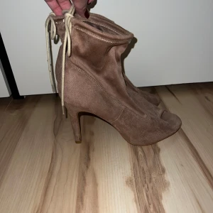 Beige boots med klack från Jenny Fairy - Säljer ett par snygga beige boots med klack från Jenny Fairy. De är i mocka och har en cool snörning upptill. Perfekta för höst och vår, och de ger en elegant touch till vilken outfit som helst. Aldrig använda (bara lite dammiga men fixar såklart vid försäljning) Storlek 39, köpta i Kroatien. Inte fri frakt.