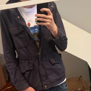 Mörkblå fieldjacket - Säljer en mörkblå peakperformance fieldjacket i bra skick.  framtill  fyra fickor man kan även tajta till den i midjan eller tvärtom. Perfekt för höst och vår, även till vintern med någon stickad cardigan eller hoodie under. Grym för skolan. Hör av dig om du är intresserad! |S\M|                                        |Jag är 185 jackan är liten i längden och ärmarna|