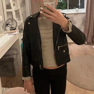 Svart skinnjacka från H&M - Säljer en snygg svart skinnjacka från H&M i storlek 128. Jackan har en cool bikerstil med dragkedja och knappar i guld. Insidan är fodrad med ett mönster av små hjärtan. Perfekt för höst och vår, och funkar både till vardags och fest! Den kostade 300 kr i butik så jag säljer den för jätte bra pris! 