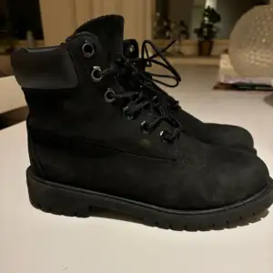 Säljer ett par svarta Timberland kängor i mocka med snörning. De är i bra skick och perfekta för höst och vinter. Skorna har en robust sula och en bekväm passform. Perfekta för både vardag och lite tuffare väder!  Skorna är i strl 37