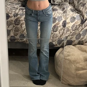 Blå bootcut jeans - Säljer ett par snygga blå bootcut jeans i storlek XS. De är lågmidjade och har en klassisk femficksdesign med dragkedja och knapp. Jag har satt dit ett resorband (se på andra bilden) i midjan för att de ska sitta tightare. Men det är inget man märker av, och man kan enkelt ta bort det bandet 🦋