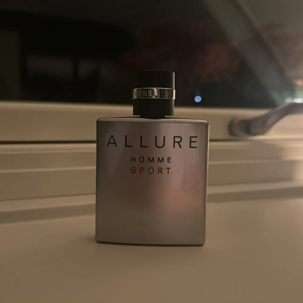 Säljer en elegant Allure Homme Sport parfym från Chanel. Flaskan är stilren och silverfärgad med svart kork och text. Perfekt för den sportiga och sofistikerade mannen. Passar både till vardags och speciella tillfällen.. Parfym.