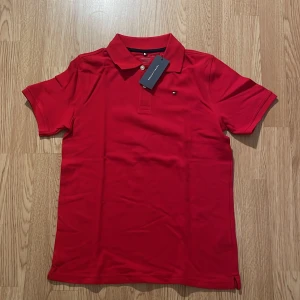 Röd pikétröja från Tommy Hilfiger - Säljer en snygg röd pikétröja från Tommy Hilfiger i helt nytt skick då den aldrig är använd 👍väldigt stilren snygg tröja som passar för vardagliga tillfällen och finare tillfällen! Endast 199 kr för denna! Kontakta oss gärna vid frågor eller funderingar mvh Sthlm garderoben!