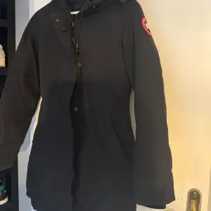 Säljer en svart Canada Goose jacka i mycket bra skick. Den har en dragkedja och knappar framtill, samt en broderad logga på ärmen. Perfekt för kalla vinterdagar med sin varma och skyddande design. Pälsen är borttagen då jackan var på kemtvätt men ingår självklart. Pris kan diskuteras, hör av er för ytligare frågor eller kvitto. 