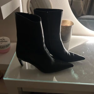 Svarta boots med spetsig tå - Snygga svarta boots i skinn med spetsig tå och klack. Perfekta för höst och vinter, dessa boots ger en elegant touch till vilken outfit som helst. De är i mycket bra skick och redo att användas för både vardag och fest. Nypris var 1950kr men säljer nu för 500!