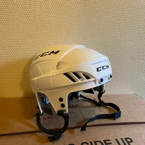 Vit hockeyhjälm från CCM - Säljer en vit hockeyhjälm från CCM i mycket bra skick. Hjälmen har justerbara remmar och ventilationshål för extra komfort. Perfekt för hockeyträning eller match. Passar de flesta huvudstorlekar.