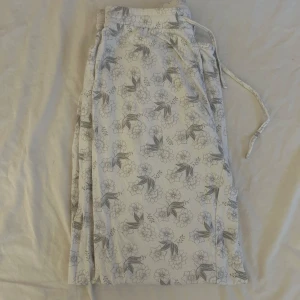 Blommiga pyjamas byxor från Twilfit - Säljer ett par supermysiga pyjamas byxor från Twilfit i storlek M. De är vita med ett fint blommigt mönster i grått och har en bekväm resår i midjan. 🌸