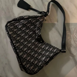 Snygg axelväska - Säljer en snygg axelväska med ett coolt mönster i svart och vitt. Väskan har en praktisk dragkedja och en axelrem. Perfekt för att ge din outfit en extra touch! 🖤Den är oanvänd och i nyskick!🔥