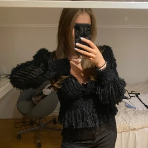Snygg blus - Säljer en superfin svart blus med volangdetaljer. Den har långa ärmar och en tight passform som framhäver figuren. Perfekt för höst och vinter, och funkar lika bra till fest som till vardags. Toppen är i mycket bra skick och redo för en ny ägare!