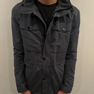 Grå fieldjacket J.Lindberg  - Säljer en stilren grå field jacket ifrån J Lindberg mycket bra skick.  Perfekt för höst och vinter, med långa ärmar och flera fickor. Passar både till vardags och lite finare tillfällen. Hör av er vid minsta lilla fundering!