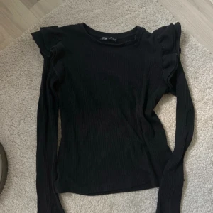 Svart långärmad topp från Zara - Säljer en svart långärmad topp från Zara i mycket bra skick. Den har volangdetaljer vid axlarna. 🖤