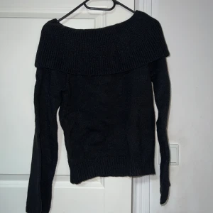 Svart offshoulder stickad tröja - Säljer en superfin svart stickad tröja med offshoulder-design. Perfekt för höst och vinter, den är både stilren och mysig. Tröjan har långa ärmar och en bred krage som ger en elegant touch. Passar perfekt till både jeans och kjol!
