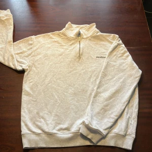 Grå tröja med dragkedja från Woodbird {M} - Säljer en snygg grå tröja från Woodbird i mycket bra skick. Den har en halv dragkedja och en liten logga på bröstet. Perfekt för både vardag och chill. Tröjan är mjuk och bekväm, perfekt för höst och vår. Dock finns det två ställen där det har nöts upp lite (där av bra pris), men det ör inget som syns om man inte letar noggrant. Nypriset låg på ungefär 800.