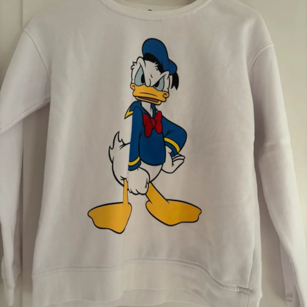 Säljer en supercool vit tröja med Kalle Anka-tryck från Cubus. Perfekt för dig som älskar Disney! Tröjan är i bomull och polyester, vilket gör den både bekväm och hållbar. Passar perfekt för vardagsbruk eller chill dagar hemma. 🦆✨            Köparen betalar frakten. . Tröjor & Koftor.