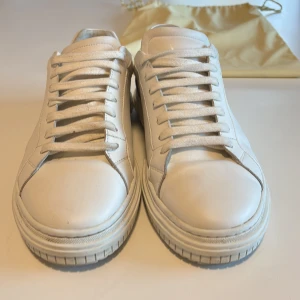 Vita sneakers från Axel Arigato - Säljer ett par stilrena vita sneakers från Axel Arigato i mycket bra skick. De är gjorda i skinn och har klassisk snörning. Perfekta för både vardag och fest! Kommer med originalpåse. Pris går o diskutera.