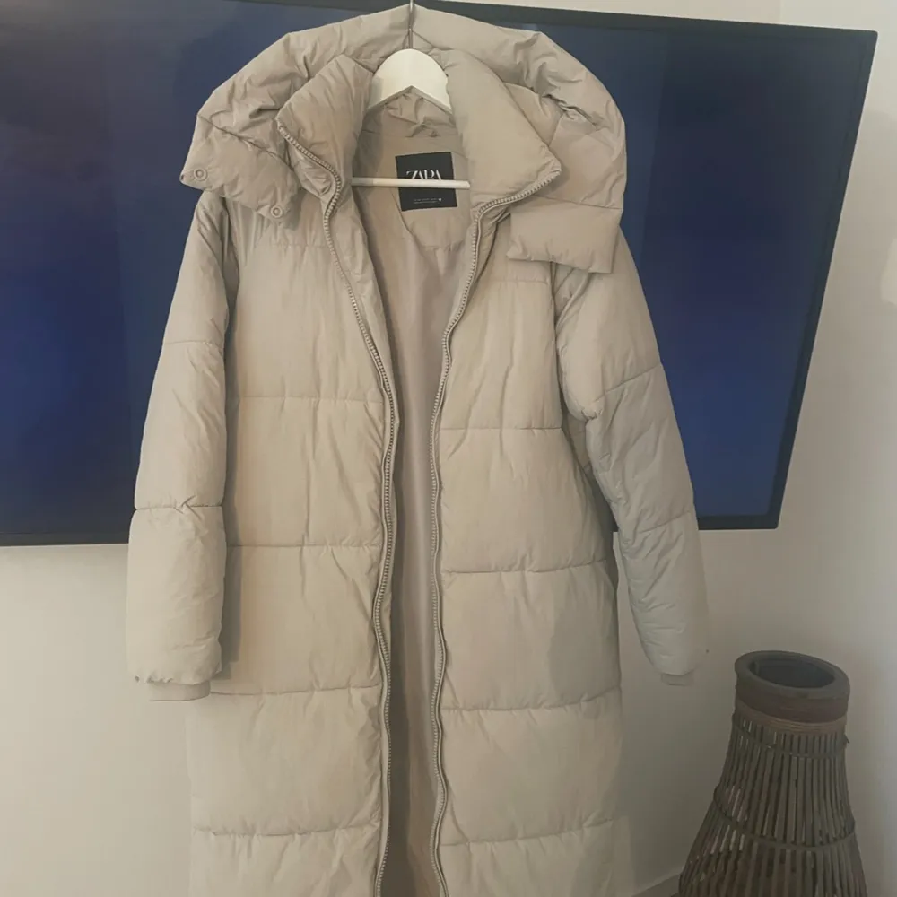 Intresse koll på denna tjocka varma dunjackan i fin ljus beige färg, går att knäppa upp på sidorna för att få slitsar på jackan, luvan och kragen går att knäppa så att ingen rusk eller kyla tränger in vid dåligt snöväder, tål - 30 grader kyla . Takit.