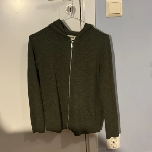 Grön hoodie med dödskalle från Zadig & Voltaire - Säljer en cool grön hoodie från Zadig & Voltaire med en stor vit dödskalle på ryggen. Den har dragkedja framtill och är i mycket bra skick. Perfekt för höst och vinter när du vill ha en stilren men edgy look. Passar både till vardags och chill kvällar. Ändast 600kr. 162 cm