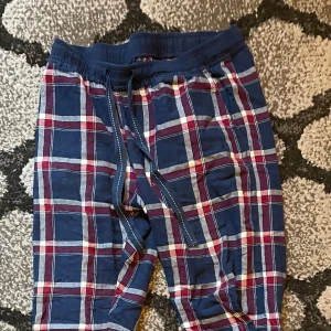 Rutig mjukisbyxa i blått och rött - Säljer ett par superbekväma mjukisbyxor med rutigt mönster i blått, rött och vitt. De har en elastisk midja med snörning för perfekt passform. Perfekta för en chill dag hemma eller en avslappnad promenad. 🛋️