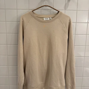 Beige sweatshirt från Weekday - storlek S - Säljer en stilren beige sweatshirt från Weekday i mycket bra skick. Den har en klassisk rund hals och långa ärmar, perfekt för både höst och vår. Materialet känns mjukt och skönt, vilket gör den idealisk för vardagsbruk. Passar perfekt för en avslappnad look!