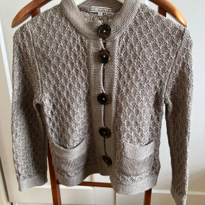 Grå stickad kofta från Dagmar - Säljer en superfin grå stickad kofta från Dagmar i storlek S. Den har ett snyggt mönster och stora knappar framtill. Perfekt för alla årstider och den är i mycket bra skick. Passar både till vardags och lite finare tillfällen. 🧥✨