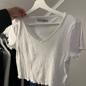 Topp lager157 - Säljer en superfin enkel vit ribbad topp från lager 157 i storlek XS. Den har en v-ringad hals och korta ärmar, perfekt för sommardagar. Toppen är croppad med en söt volangkant nedtill. Passar både till vardags och fest! Säljer den för 40kr + frakt eller prisförslag🥰