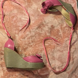Rosa kilklackar med rosett - Säljer ett par snygga rosa kilklackar från Street Super Shoes i storlek 39. De har en söt rosett på framsidan och en bekväm kilklack i beige. Perfekta för sommarens fester eller en dag på stan. Använda men i bra skick!