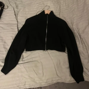 Svart croppad jacka med dragkedja - Säljer en svart croppad jacka med dragkedja framtill. Den har en hög krage och långa ärmar, perfekt för en stilren look. Passar bra till både vardag och fest. 🖤