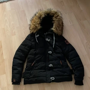 Svart Navahoo pälsjacka - En tjock och jätteskön, varm vinterjacka. Vind och vattenavisande. Inte riktig päls. Man kan ta av pälsen. Insidan är fluffig och skön. Använd en hel vinter. Originalpris är 1236kr på zalando. (Lägger upp annonsen igen)