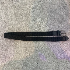 Svart flätat bälte - Säljer ett snyggt svart flätat bälte. Det har en enkel design med en klassisk spänne i metall. Perfekt för att ge en stilren touch till vilken outfit som helst. Passar både till vardags och fest!