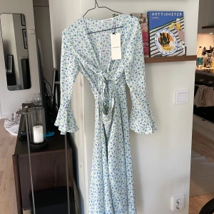 Adooreklänning - Helt oanvänd adooreklänning i strl 34, tyvärr för liten för mig. Öppen vid magen, knut över brösten och trumpetarmar. 