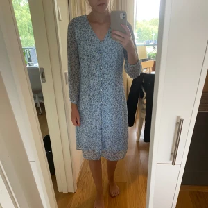 Blommig klänning  - Blå blommig klänning från Vero Moda i storlek XS, men skulle även säga att den passar som en S. Knappar framtill. Jag är 165 cm lång. Endast använd ett fåtal gånger.