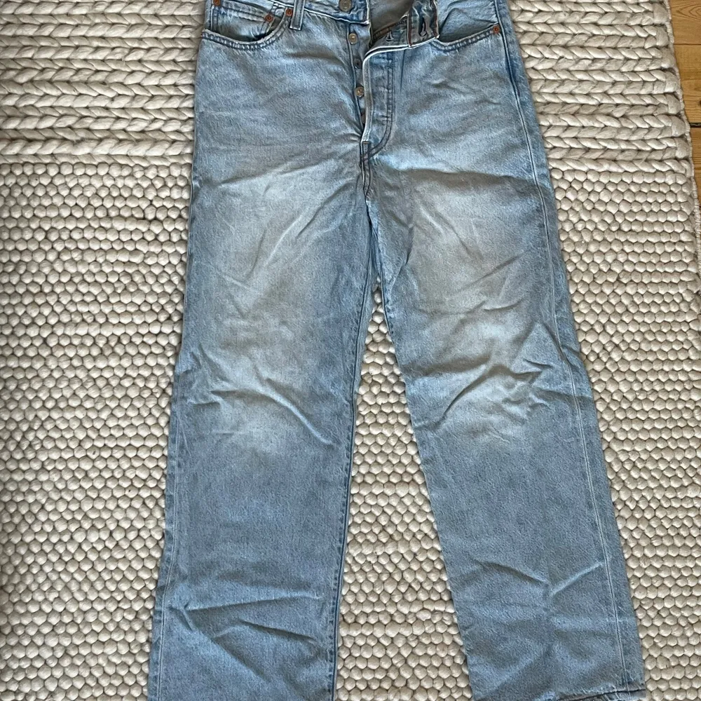 Säljer ett par Levi's Ribcage Straight jeans i ljusblå denim. De är högmidjade och har en rak passform som ger en klassisk look. Perfekta för både vardag och fest! 🕺. Jeans & Byxor.