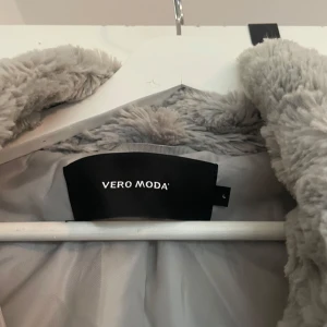 Grå pälsjacka från Vero Moda - Säljer en supermysig grå pälsjacka från Vero Moda. Den är perfekt för kalla höst- och vinterdagar. Jackan har en fluffig och mjuk yta som gör den både stilren och bekväm. Den har långa ärmar och en klassisk krage. Perfekt för att hålla sig varm och snygg samtidigt!