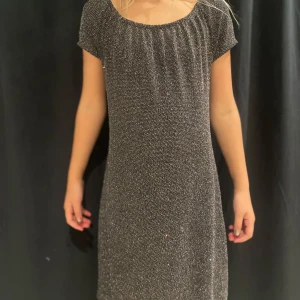 Glittrig klänning från KappAhl - Säljer en superfin glittrig klänning från KappAhl i storlek 140. Den är perfekt för festliga tillfällen med sitt glittriga mönster och kortärmade design. Klänningen har en bekväm passform och är gjord i ett mjukt material som känns skönt mot huden.