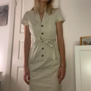 Klassisk söt beige klänning figursydd - Söt beige figursydd gullig klänning med midjeband och knappar. Från HM storlek 38 (S)