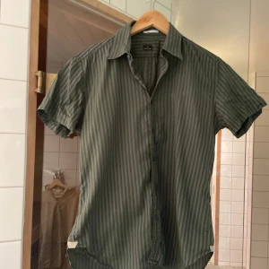 Grön randig skjorta från Paul Smith - Säljer en snygg grön randig skjorta från Paul Smith. Skjortan har korta ärmar och knappar framtill. Den är i gott skick