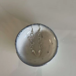 Silvriga örhängen med kedjor och koner - Snygga och moderna silvriga örhängen med en kedja av små ringar och en konformad detalj längst ner. Perfekta för att ge en edgy touch till din outfit. Passar både till vardags och fest!