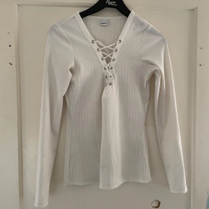 Vit ribbad tröja från Gina Tricot - Säljer en superfin vit ribbad tröja från Gina Tricot. Den har en snygg snörning framtill som ger en extra touch. Tröjan är långärmad och perfekt för både vardag och fest. Passar perfekt till höst och vår!
