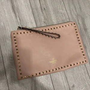 Valentino clutch - Säljer nu denna söta valentino clutch, den är i underbar skick och passar verkligen till allting.  Rosa med guldnitar 