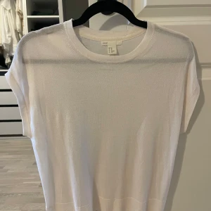 Vit kortärmad topp från H&M - Säljer en stilren vit topp från H&M i storlek S. Den är kortärmad och har en rund halsringning. Perfekt för en enkel och fräsch look. Passar bra till både jeans och kjol. 🌟
