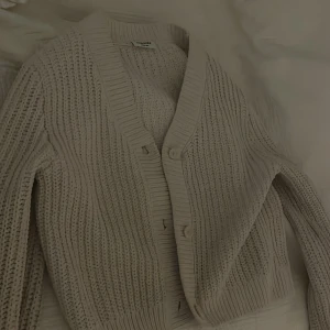Beige stickad kofta från Kappahl - Mysig beige stickad kofta från Kappahl med knappar framtill. Perfekt för kyliga dagar med sin ribbade struktur och bekväma passform. Ett måste i garderoben, kontakta mig för intresse 🤍🥰